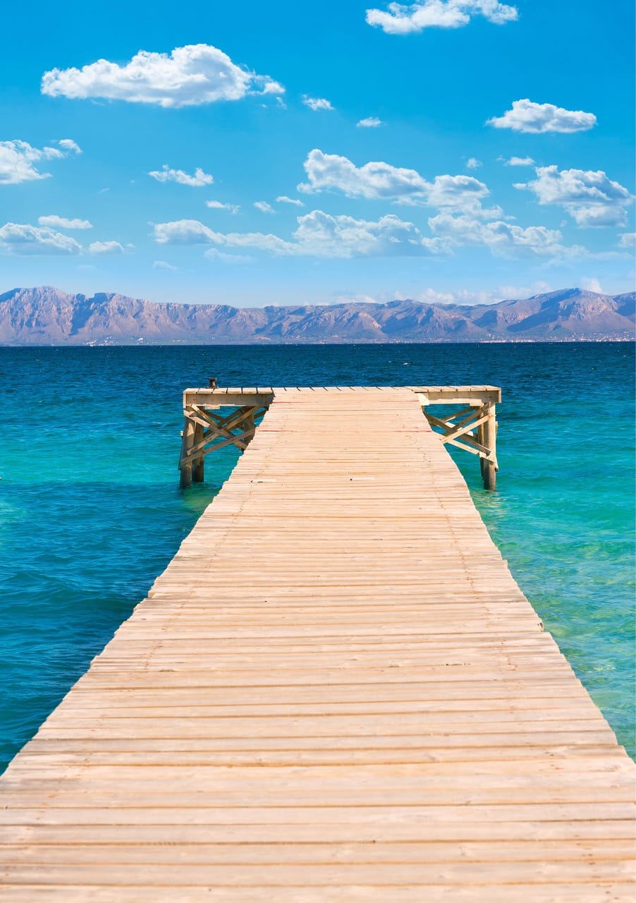 Holzsteg am Meer auf Mallorca mit Blick auf das Gebirge. Symbol für Klarheit, Richtung und persönliche Weiterentwicklung auf Fortbildungsreisen.